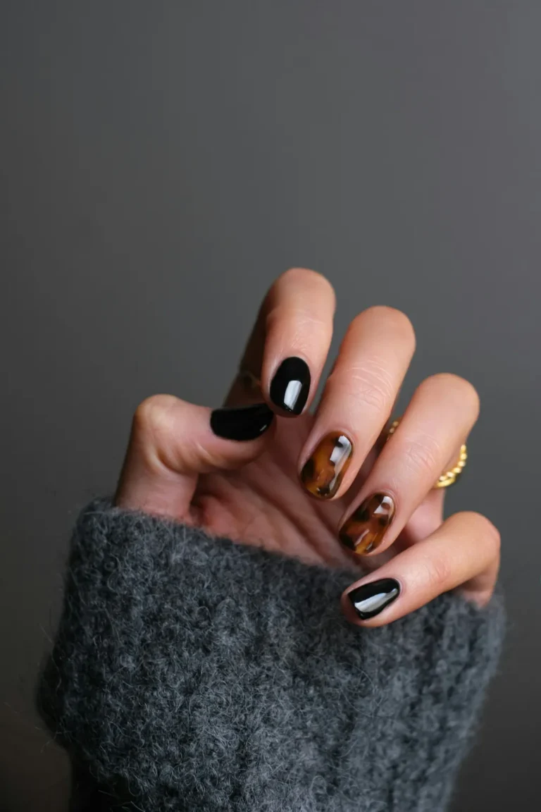 Black and tortoiseshell nails on a grey knit sleeve