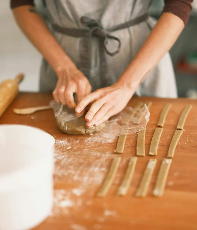 Hands cutting pasta on a wooden board