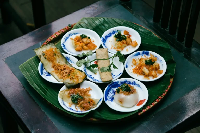Small rice cakes in blue bowls on a banana leaf