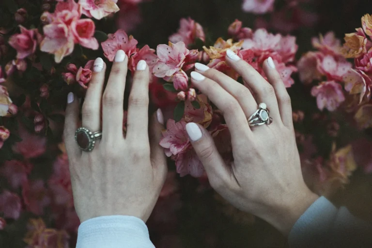 Hands with rings over pink blossoms