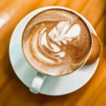 Latte with a cookie on an orange table