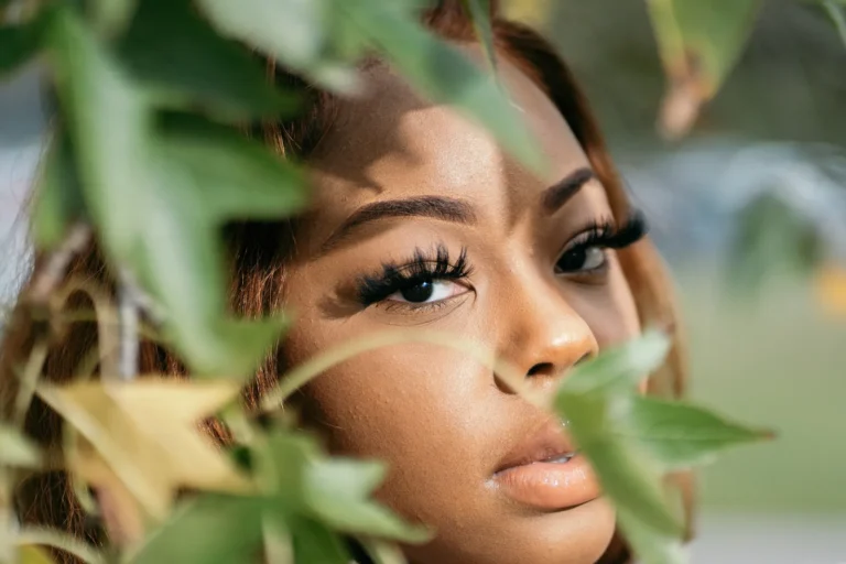 Client with wispy lashes among green leaves