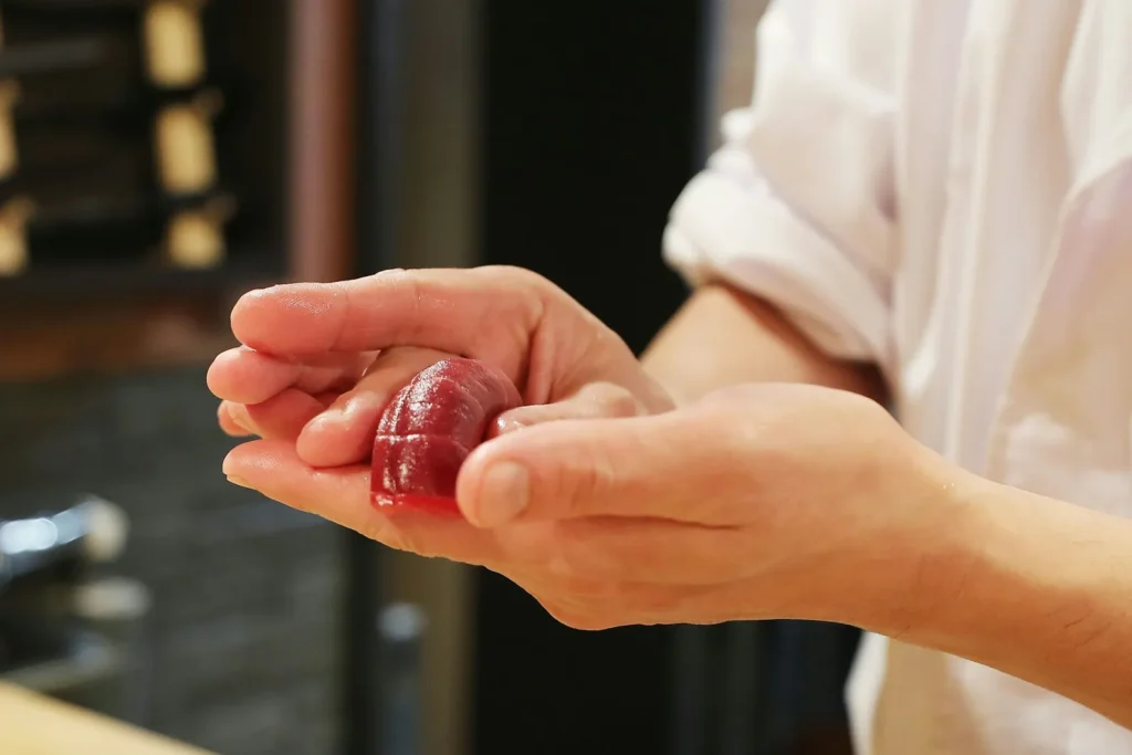 Chef shaping a piece of tuna nigiri by hand