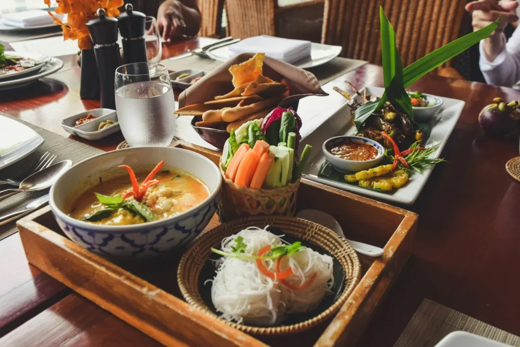 Soup, noodles and herbs served on a wooden tray