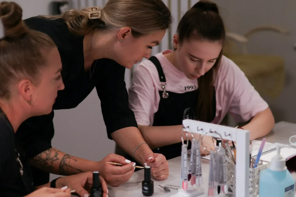 Students practicing lash extensions at a long table