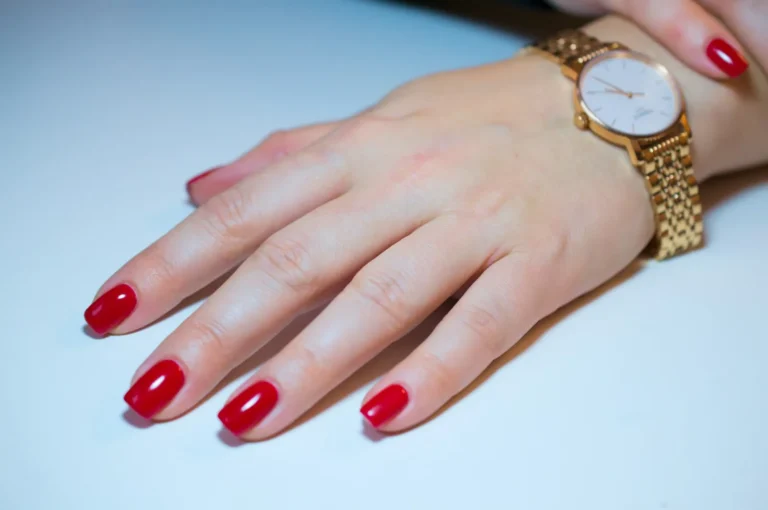 Classic red manicure with a gold watch