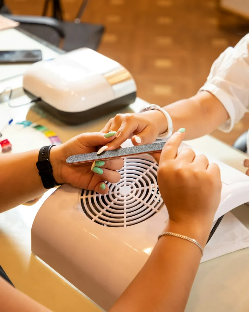 Nail tech filing a client's nails at the table