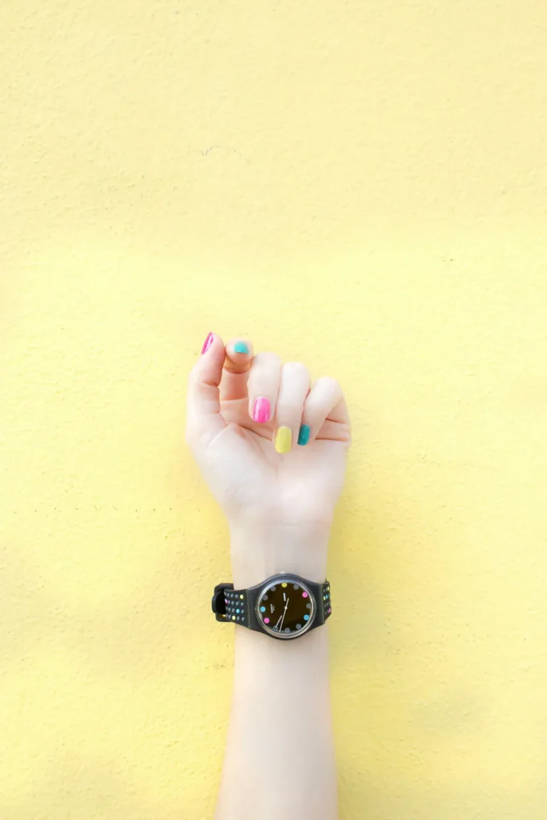 Rainbow manicure against a yellow wall