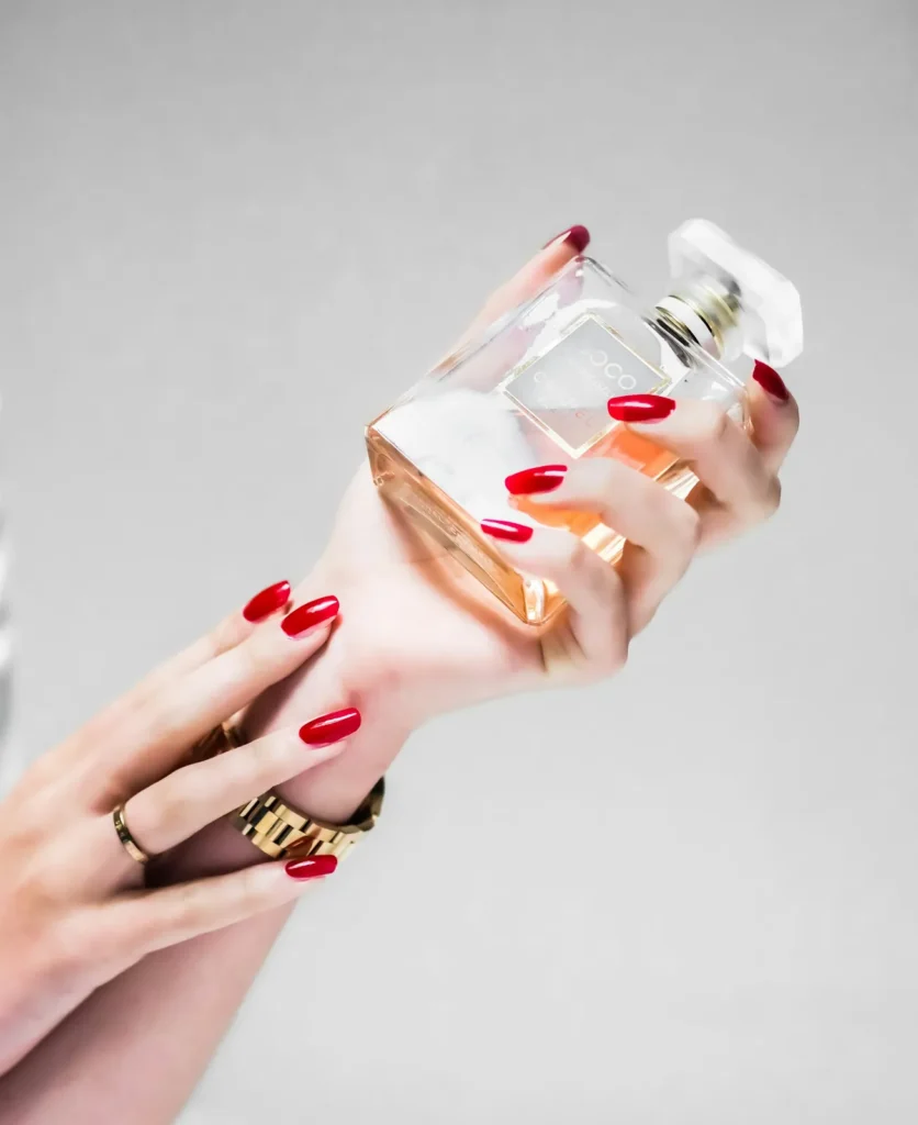 Red manicure holding a perfume bottle
