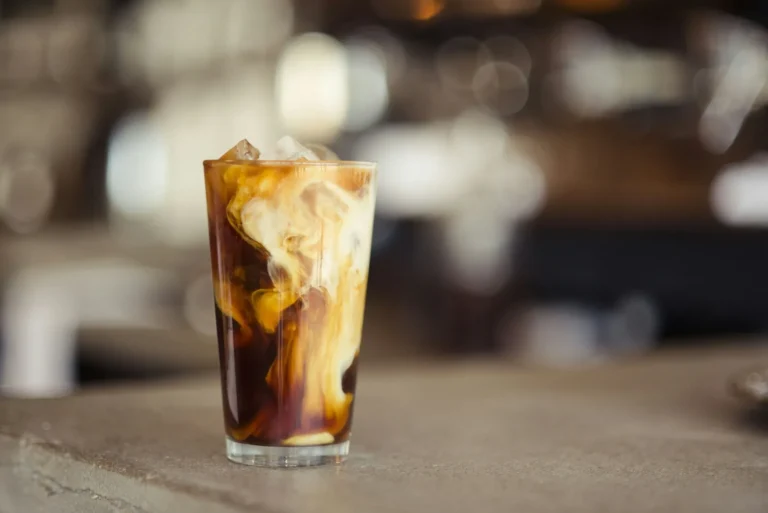 Iced coffee with condensed milk swirling in the glass