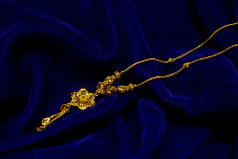 A gold chain with a flower charm on velvet