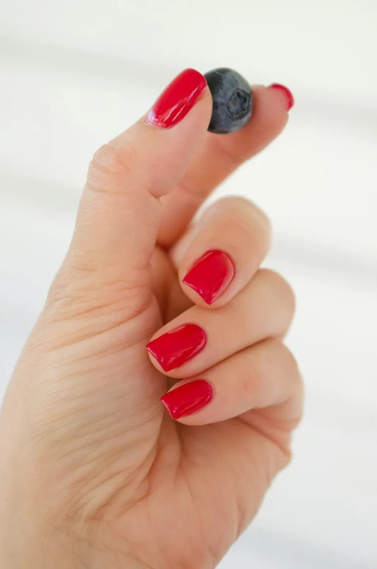 Red nails holding a blueberry