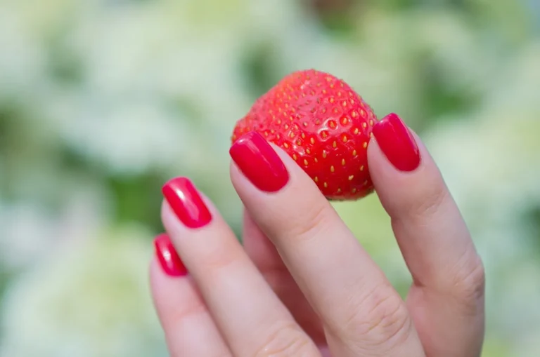 Red nails holding a strawberry