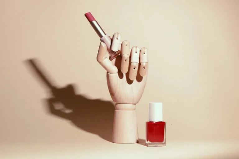 Wooden hand with a red polish brush