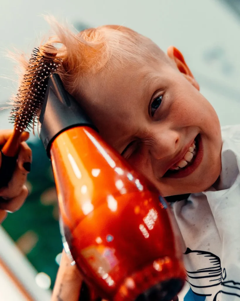 Kid laughing with a hair dryer